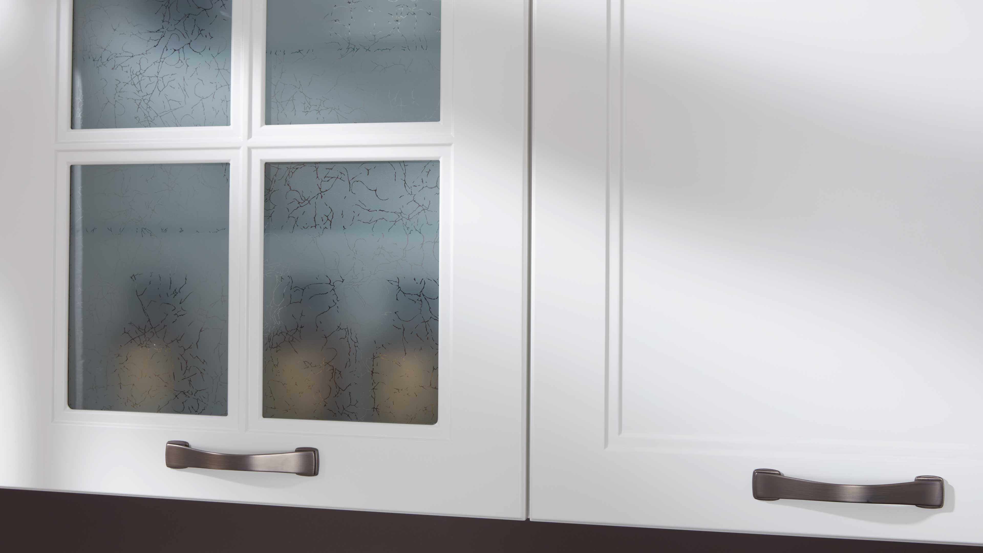 Zwei weiße Küchenschranktüren mit dunklen Griffen, links vier mattierte Glasfelder mit feiner Rissstruktur, rechts glatte Füllung.