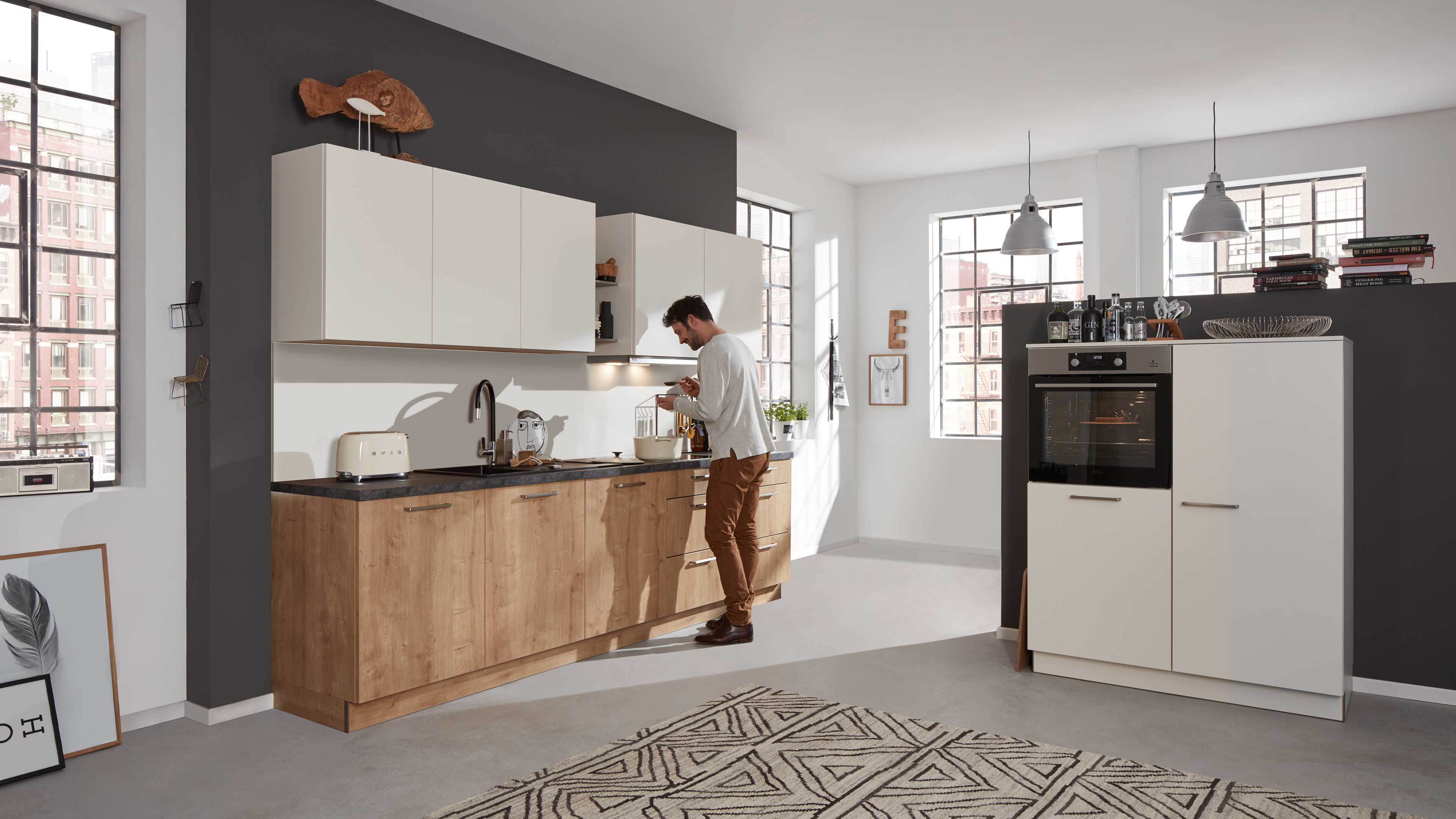 Einbauküche mit Holzoptik-Unterschränken, matten weißen Oberschränken, dunkler Arbeitsplatte und Hochschrank mit Backofen.