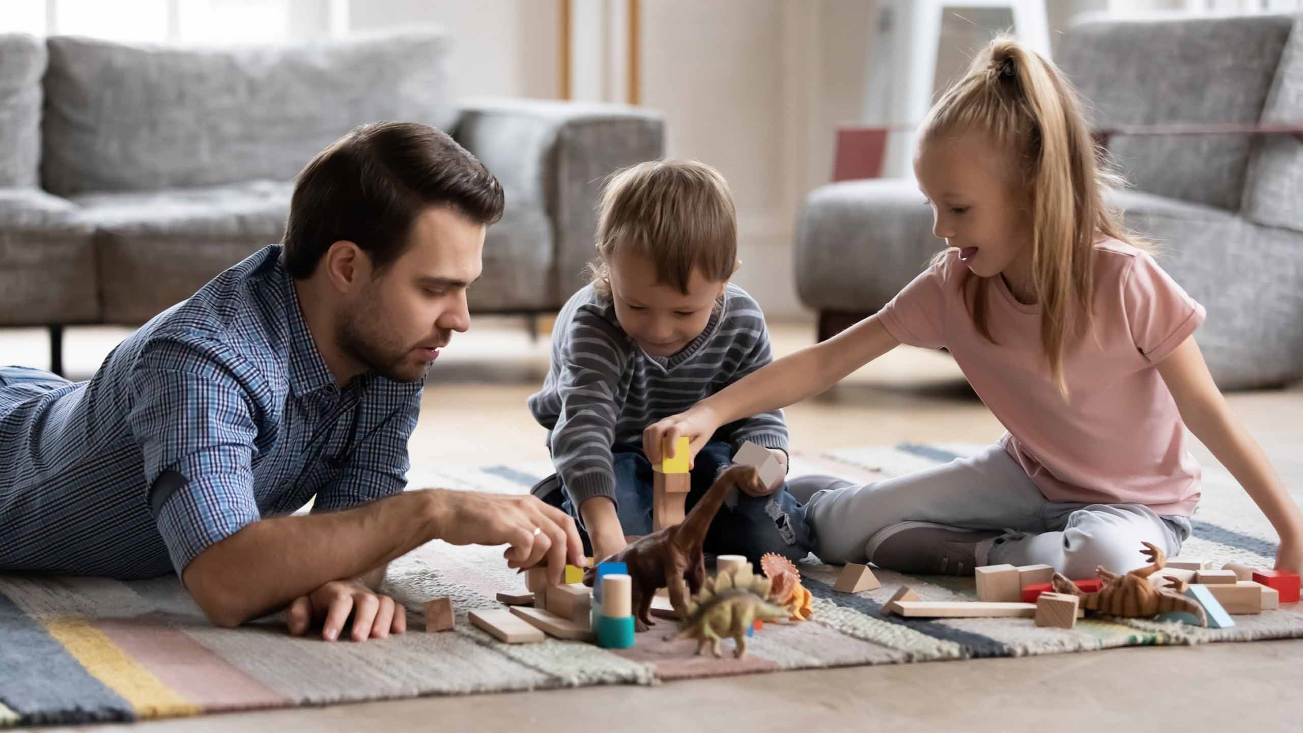 Familie spielt zusammen auf dem Teppich